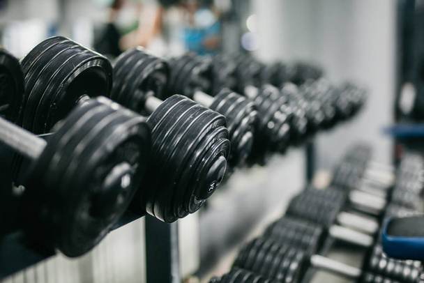 a row of black dumbbells lie in the hall - Foto, imagen