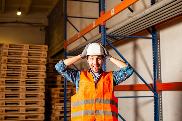 Excited worker touching his protective helmet in the warehouse - Valokuva, kuva