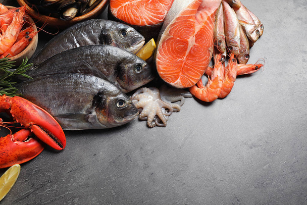 Fresh fish and different seafood on grey table, flat lay. Space for text - Photo, Image