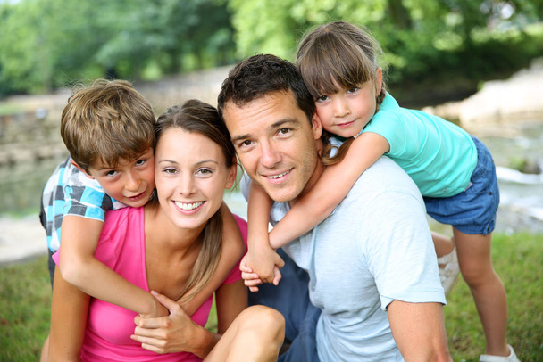 Family relaxing by river in countryside - Foto, imagen