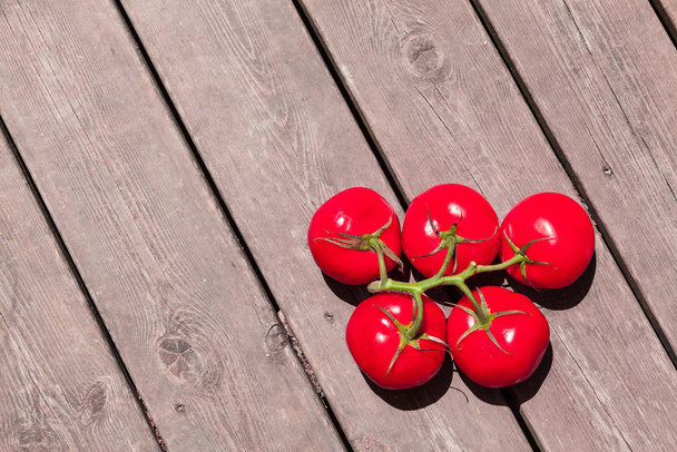 Пять красных помидоров в форме олимпийских кругов на деревянном полу
 - Фото, изображение
