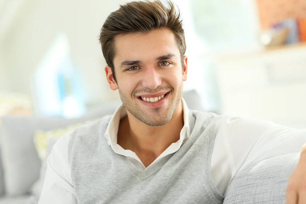 Portrait of smiling casual guy sitting in sofa - Zdjęcie, obraz