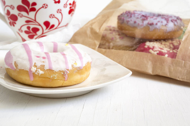 Donut on plate and bag full of donuts on background - Photo, Image