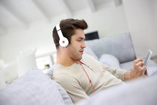Young man with headphones watching movie on tablet - Fotoğraf, Görsel