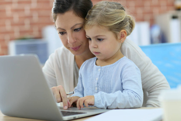 Mother and little girl using laptop computer - Foto, afbeelding