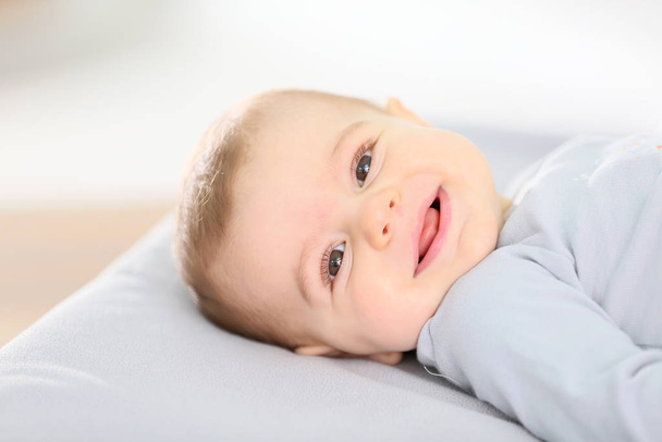 Portrait of smiling baby boy laying on changing table - Foto, Bild