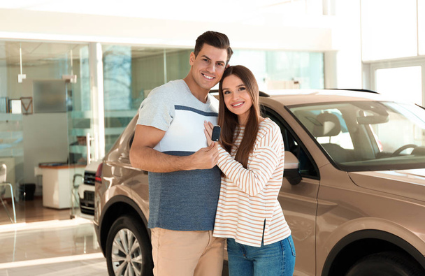 Happy couple with car key in modern auto dealership - Photo, image