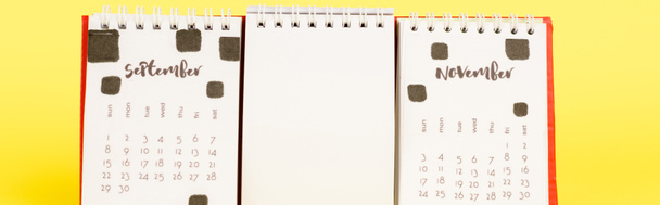 Panoramic shot of calendar with autumn months and empty blank on yellow background - Photo, Image