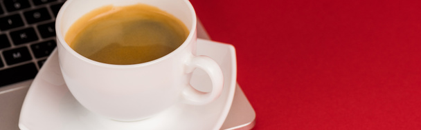 Close up view of coffee cup on laptop on red background, panoramic shot - Fotoğraf, Görsel