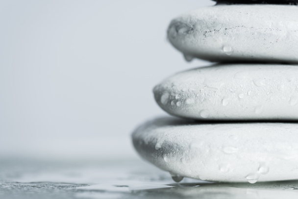 Makro shot z białych kamieni zen w kroplach wody na mokrym szkle izolowane na szarości - Zdjęcie, obraz