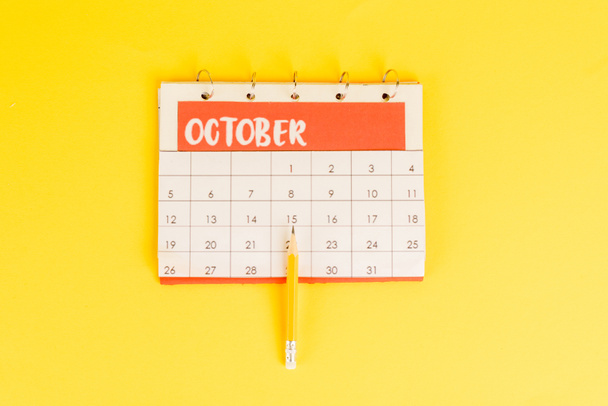 Bovenaanzicht van potlood op kalender met november maand op gele achtergrond - Foto, afbeelding