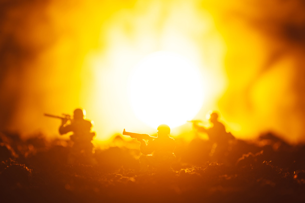 Сцена боя с игрушечными воинами в дыму и закате на заднем плане
 - Фото, изображение