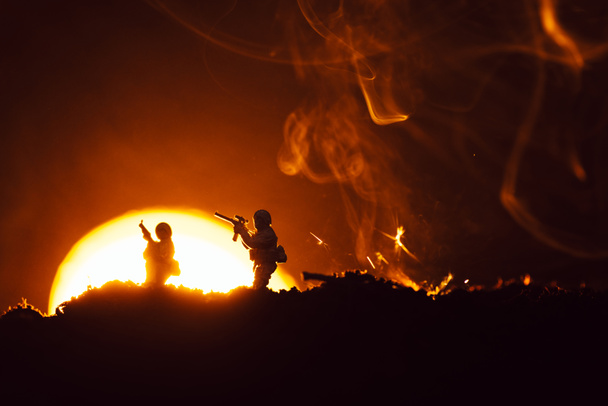 Kampfszene mit Spielzeugsoldaten auf dem Schlachtfeld mit Rauch und Sonnenuntergang im Hintergrund - Foto, Bild