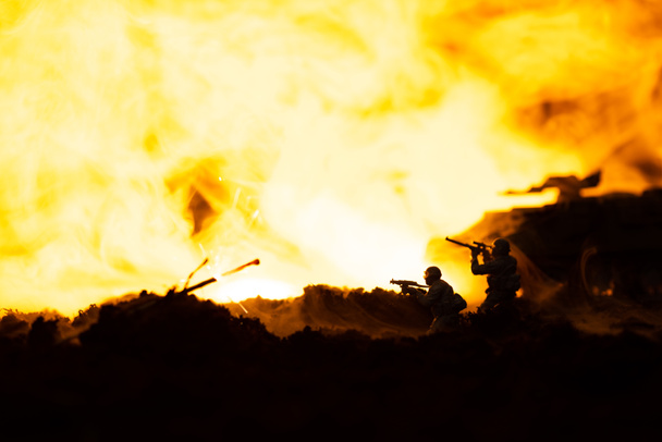 Battle scene with toy soldiers and tank on battleground with fire at background - Foto, afbeelding