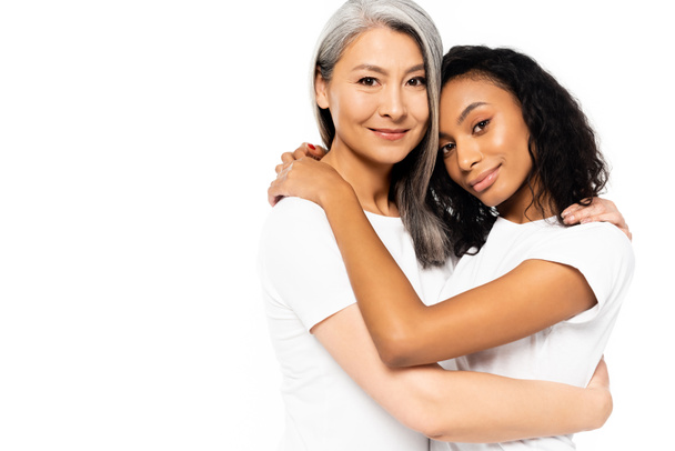 happy african american and asian women hugging isolated on white  - Фото, изображение