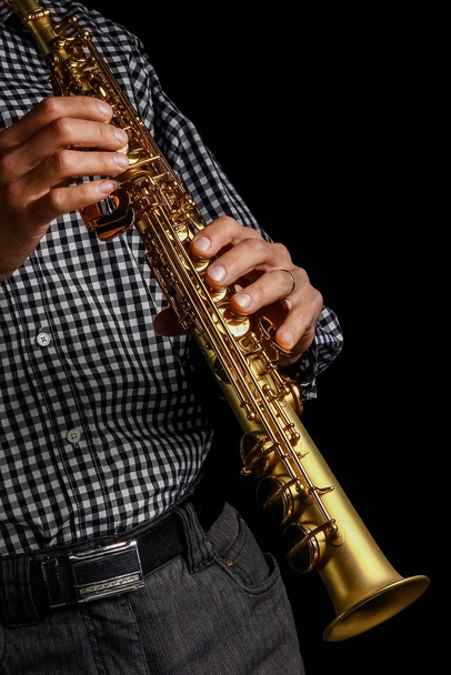 soprano saxophone in hands on a black background - Fotoğraf, Görsel