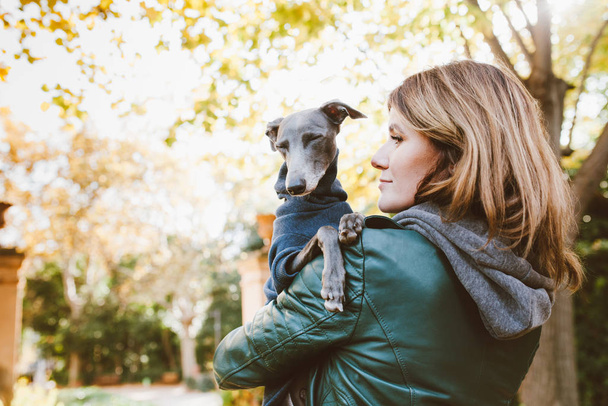 Dog and woman, portrait of happy puppy with close eyes and young woman. Handsome young lady is hugging and cuddling his cute Italian Greyhound god. Domestic pets concept - Photo, Image
