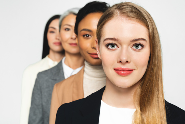 селективный фокус четырех привлекательных и мультикультурных деловых женщин, смотрящих в камеру, изолированную на белом
  - Фото, изображение