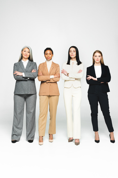 donne d'affari multiculturali in giacca e cravatta con le braccia incrociate sul bianco
  - Foto, immagini