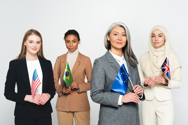 πολυπολιτισμικές επιχειρηματίες με σημαίες από διαφορετικές χώρες απομονωμένες σε λευκό  - Φωτογραφία, εικόνα