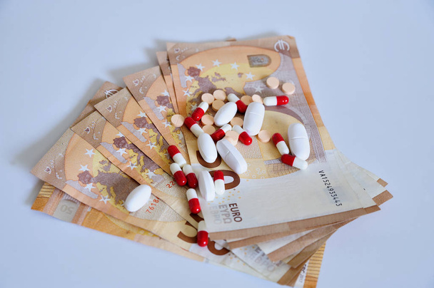 Medikamente und Geld in Euro auf weißer Fläche. - Foto, Bild