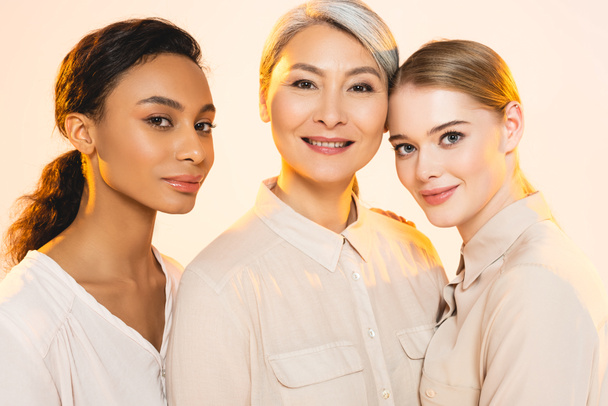 three beautiful multicultural women smiling isolated on beige  - Fotó, kép