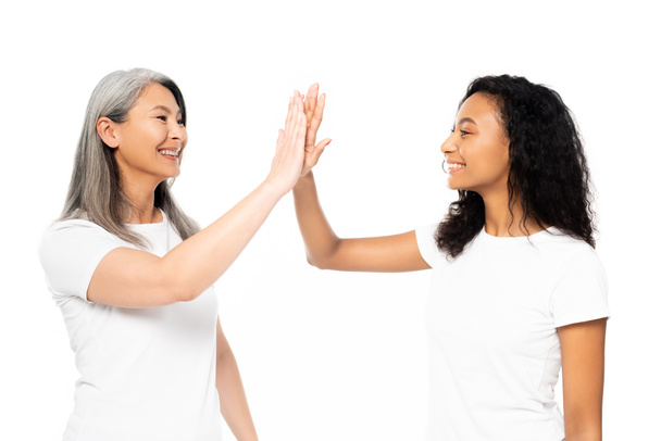 happy african american and asian women giving high five isolated on white  - Fotó, kép