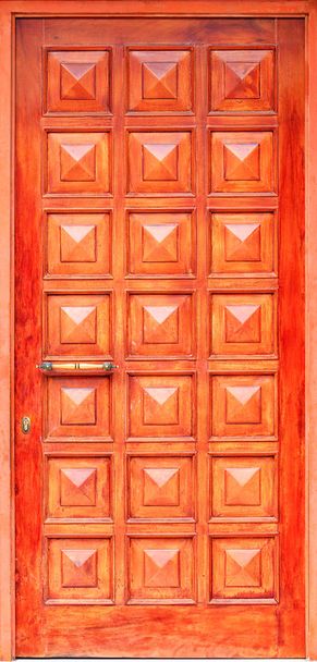 Oude oranje houten entreedeuren met bronzen handvat en symmetrische vierkante panelen in Griekse stijl. - Foto, afbeelding