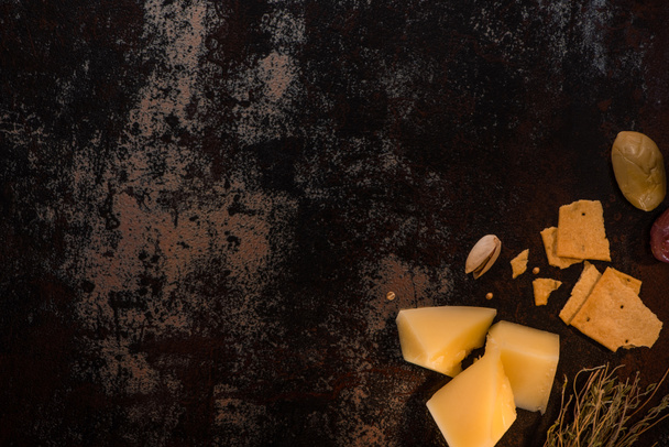 pohled shora na sýrový talíř s pistáciemi, olivami a sušenkami na ošlehaném povrchu - Fotografie, Obrázek