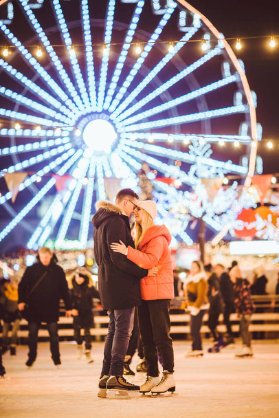 couple hugging in Saint Valentines Day. Young romantic pair having fun outdoors in winter. St. Valentines Day at city ice rink. New Year holidays. active date ice skating on ice arena on Christmas - Photo, Image