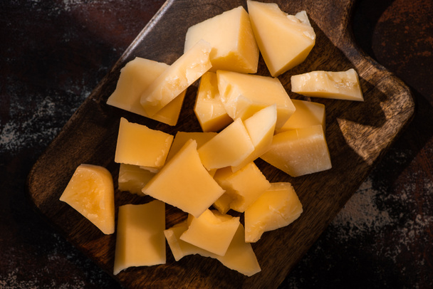 vista superior de bandeja de madeira com queijo Grana Padano na superfície resistida à luz solar
 - Foto, Imagem