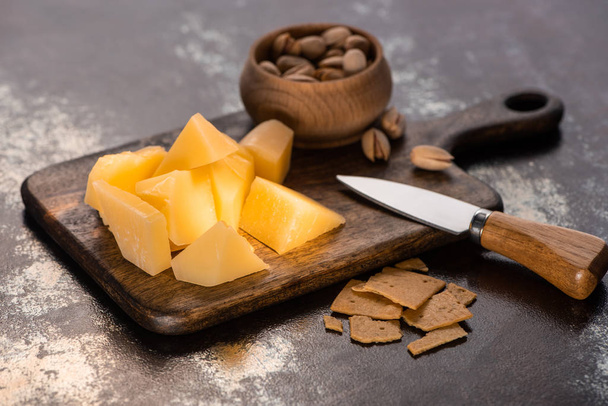 チーズプレートにグラナパダーノ、クラッカー、ピスタチオナイフの近く - 写真・画像