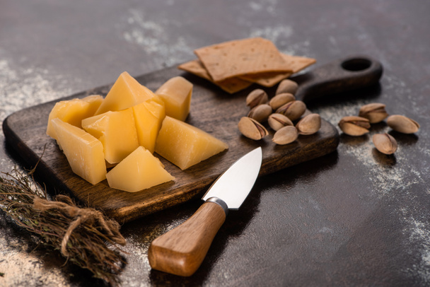 cheese platter with Grana Padano, crackers and pistachios near knife - Foto, immagini