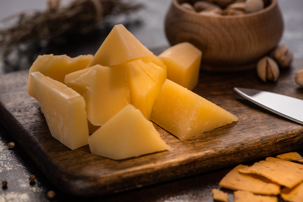 vista ravvicinata del piatto di formaggio con Grana Padano, cracker e pistacchi vicino al coltello
 - Foto, immagini
