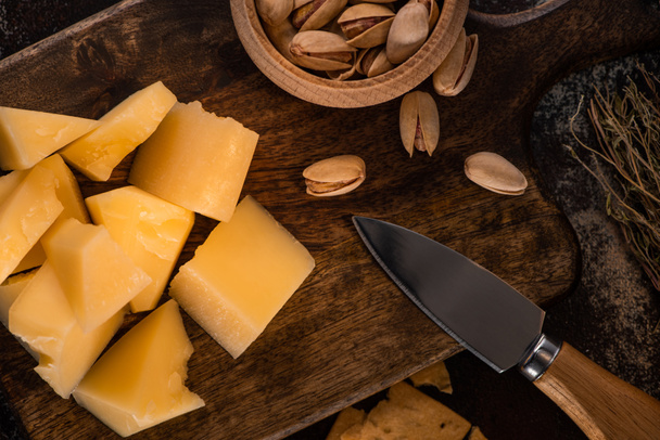 πάνω όψη πιατέλας τυριού με Grana Padano και φιστίκια κοντά σε μαχαίρι - Φωτογραφία, εικόνα