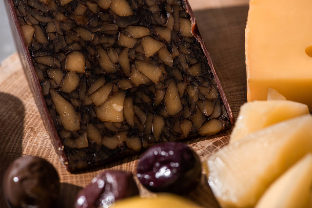 Selektywne ukierunkowanie sera orzechowego z oliwkami na drewniane tło - Zdjęcie, obraz
