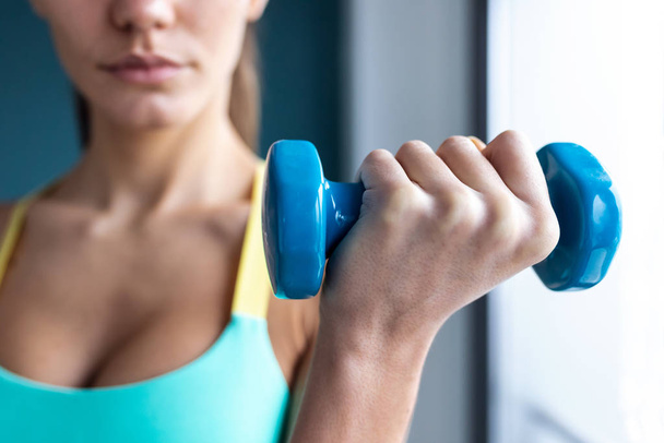 Sporty young woman doing muscular exercise with dumbbells on gym. - Foto, immagini