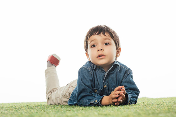 cute boy looking away and lying on grass isolated on white  - Photo, image