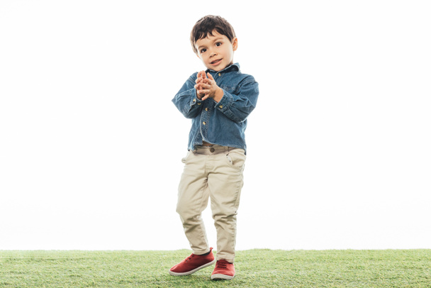 smiling and cute boy standing on grass isolated on white  - Photo, Image