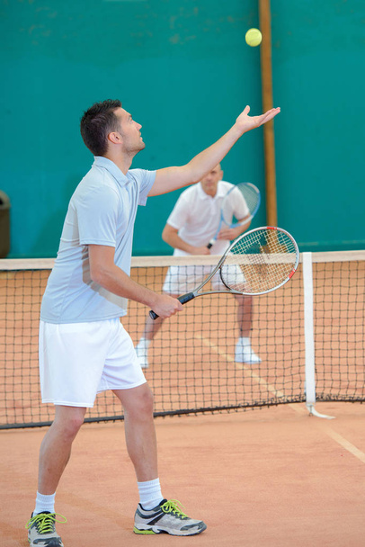 Junger Mann leistet Tennisdienst - Foto, Bild