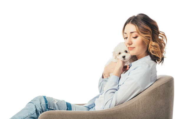 woman holding Havanese puppy and sitting on armchair isolated on white - Foto, immagini