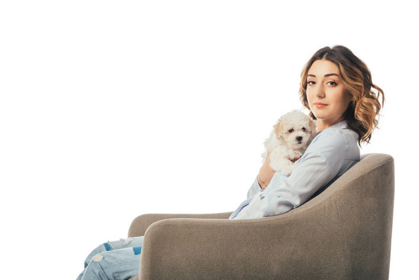 woman holding Havanese puppy and sitting on armchair isolated on white - Foto, immagini