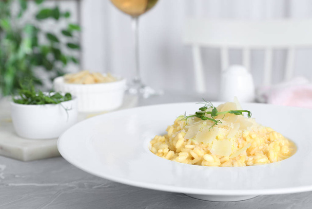 Delicious risotto with cheese on grey marble table indoors - 写真・画像
