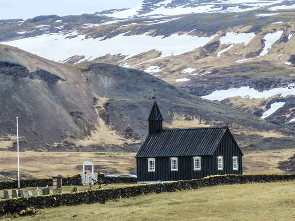 Black wooden church in front of a mountain chain in Budir, Iceland - Photo, image