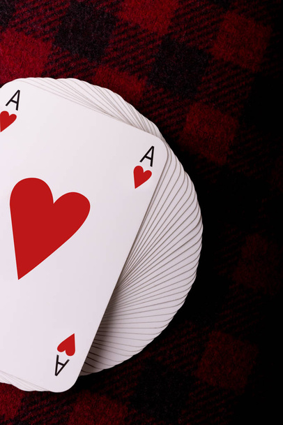 Baralho cheio de cartas de baralho com ás de corações no topo deitado em xadrez xadrez. Foto vertical. Lugar para texto
 - Foto, Imagem