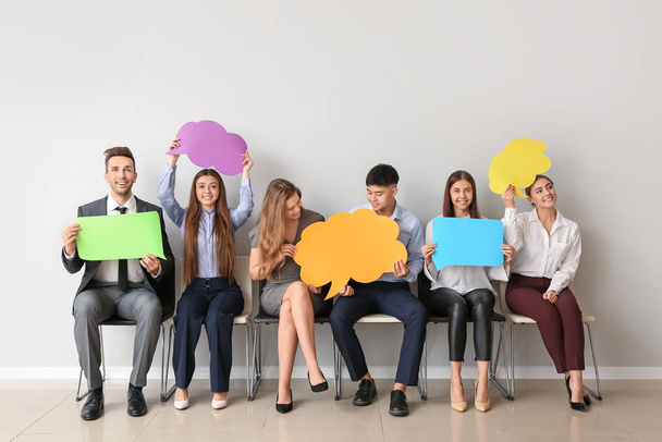 Group of business people with blank speech bubbles near light wall - Photo, Image