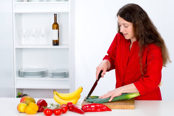 tmavovlasá žena s červenou košilí v kuchyni - Fotografie, Obrázek