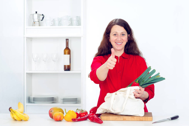 tmavovlasá žena s palcem nahoru v kuchyni - Fotografie, Obrázek