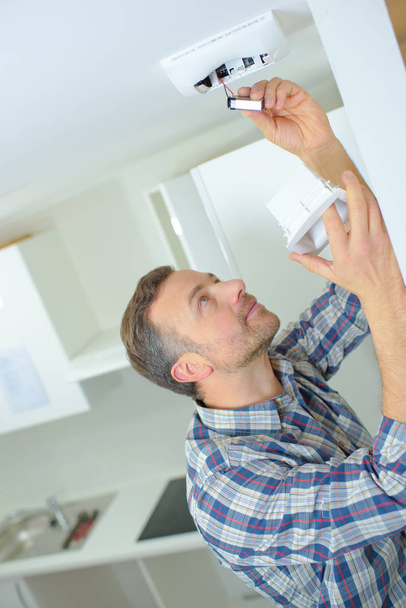 Safety conscious man fitting a fire smoke alarm - 写真・画像