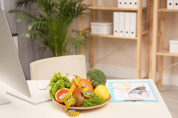 Nutritionist's workplace with fruits, vegetables, measuring tape - Foto, Bild